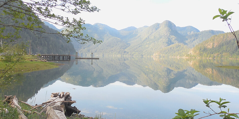 A view over a misty lake with small mountains in the background.