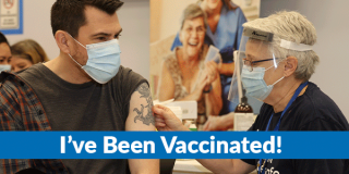 A young man with a tattoo on his shoulder gets a vaccine from an older nurse.