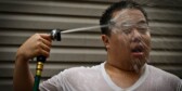 A man seeks relief during a heat wave with a garden hose shower.