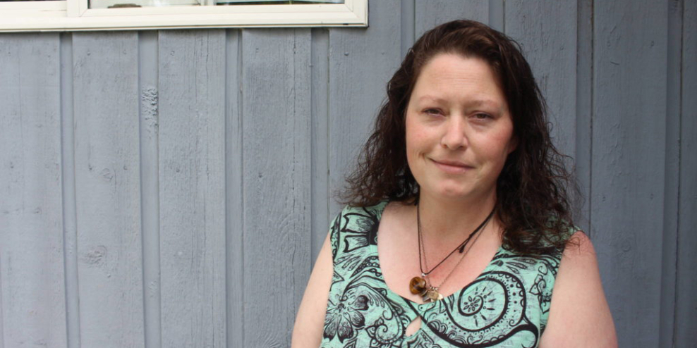 Kandi Kehler stands in front of a grey wall.