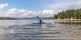 Person on kayak under blue and white sky