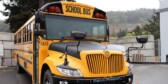 A closeup of the front of a new electric school bus on a cloudy day.