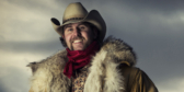 A portrait of Tim Hus in a cowboy hat and big fur coat.