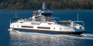 A shot of the Island Aurora ferry with a tree-covered island in the background.