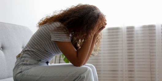 A woman sits with her head in her hands.